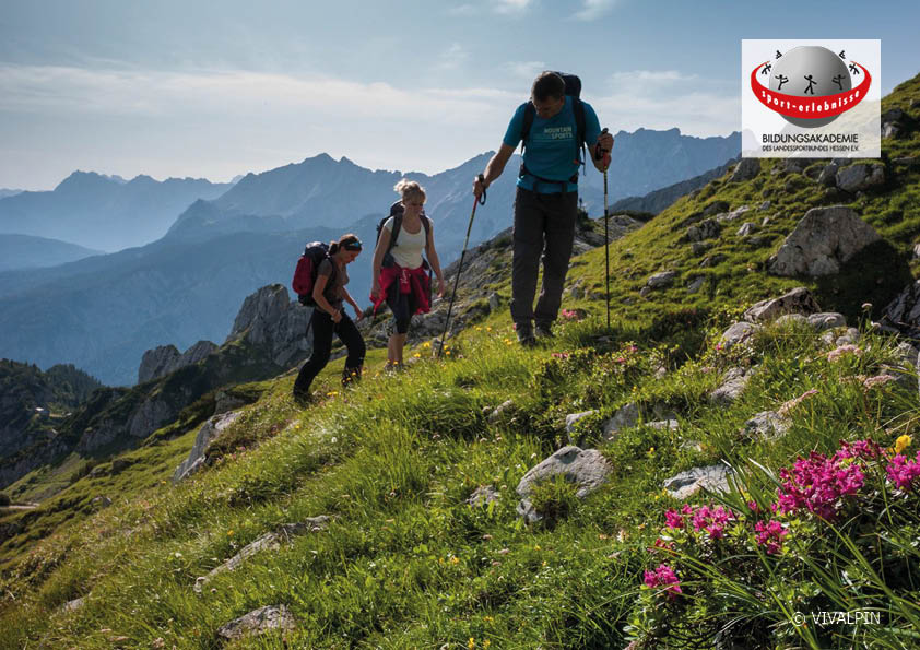 Drei Wander:innen in den Alpen im Frühjahr