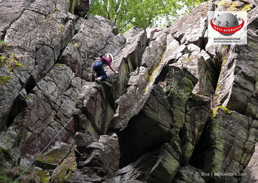 Eine Frau klettert gesichert am Naturfels