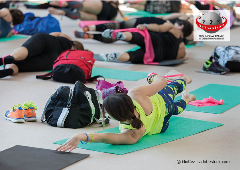Eine Gruppe Menschen auf Yoga Matten machen Sport mit Terrabändern auf einem Aktionstag Fitness und Gesundheit