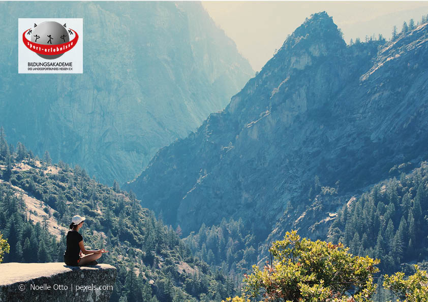 Ein Frau im Yogasitz vor Bergkulisse mit Weitblick Achtsamkeit Entspannung Retreat Yoga Wandern Freizeit Natur Berge