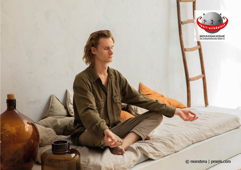 Ein Mann sitzt entspannt auf seinem Bett und meditiert Entspannung Meditation