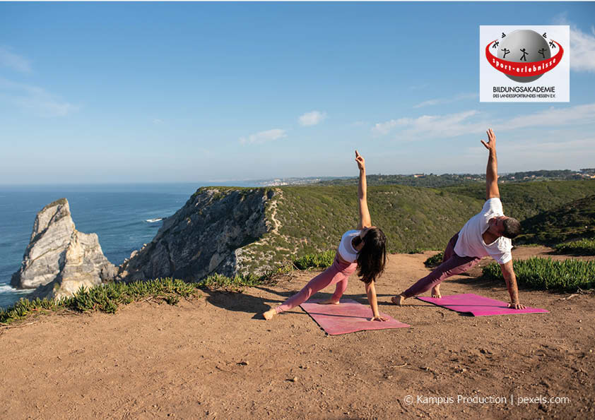 Zwei Menschen machen Yoga auf einer Klippe vor dem Meer Gesundheit Achtsamkeit Bildungsurlaub