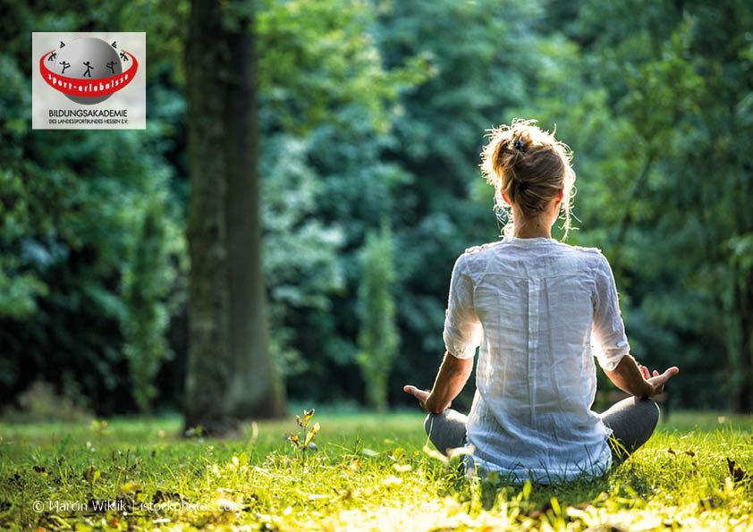 Frau sitzt im Wald und meditiert Yoga Achtsamkeit