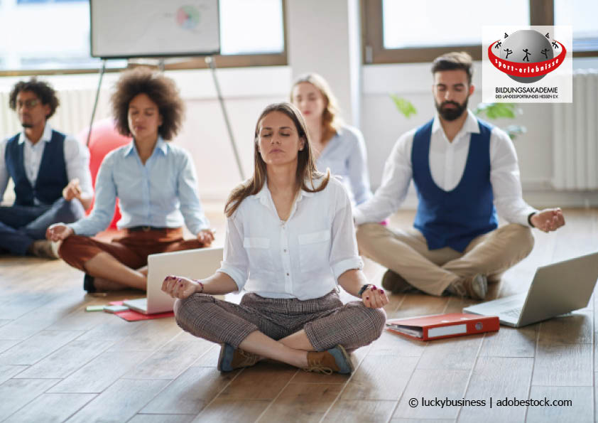 Eine Gruppe Menschen meditiert im Arbeitsalltag zur Entspannung und Stress-Prävention Bildungsurlaub
