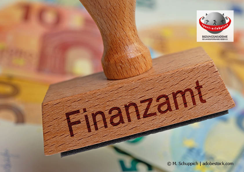 Ein Holzstempel mit der Aufschrift "Finanzamt" und im Hintergrund Euro-Geldscheine Gemeinnützigkeit Finanzen